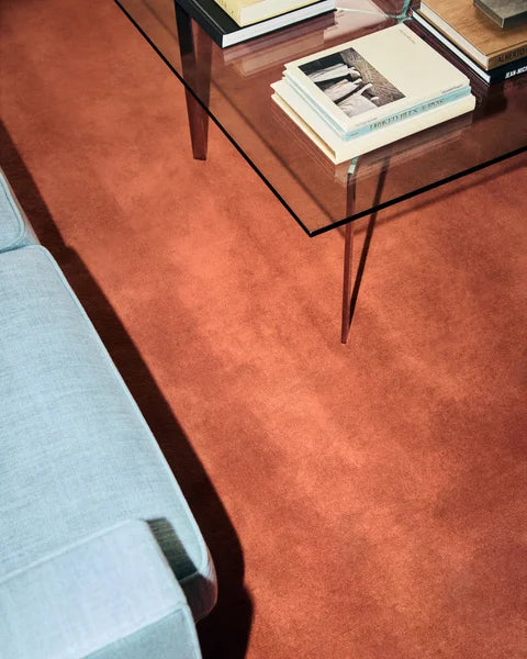 Living room with a red carpet, glass coffee table, and light blue sofa.