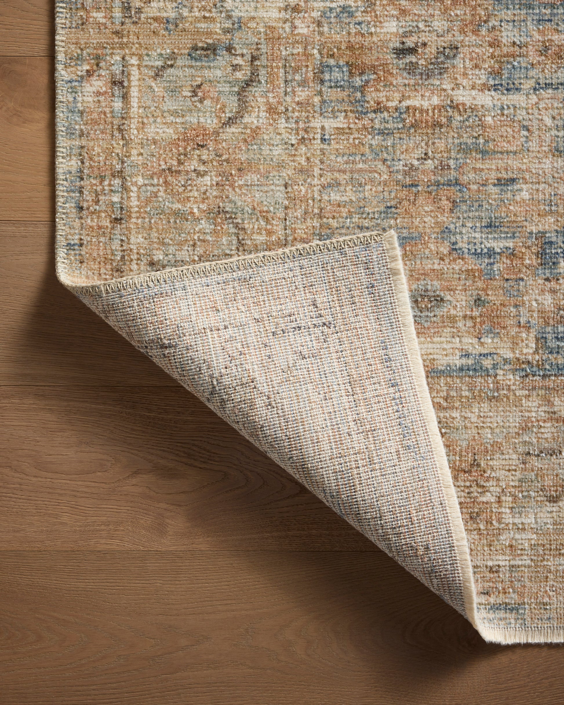 Close-up of the Heritage Ocean/Sand rug variable-pile texture with no rug cushion on wood floor